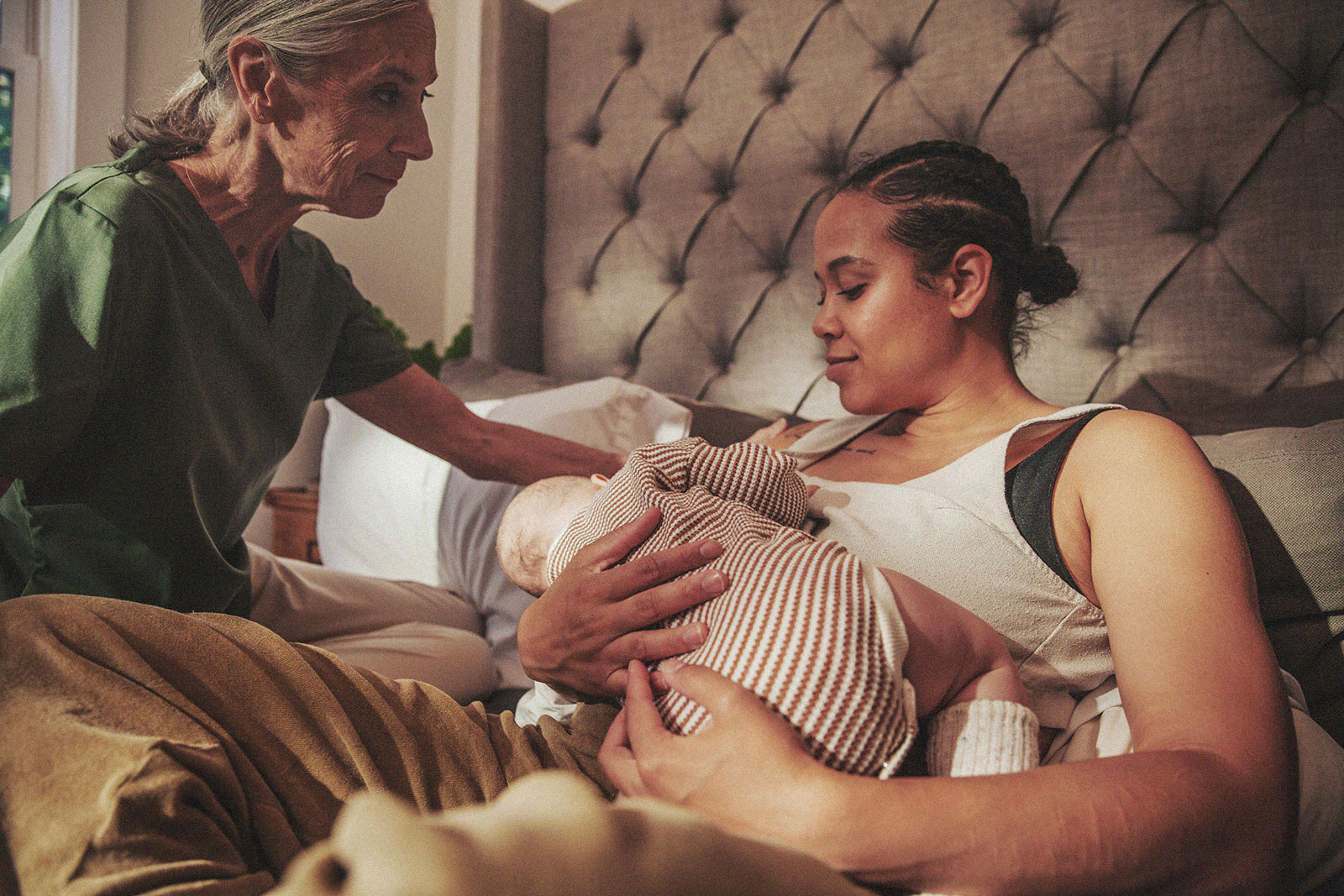 A parent lies in bed while holding an infant, with an International Board Certified Lactation Consultant offering support.
